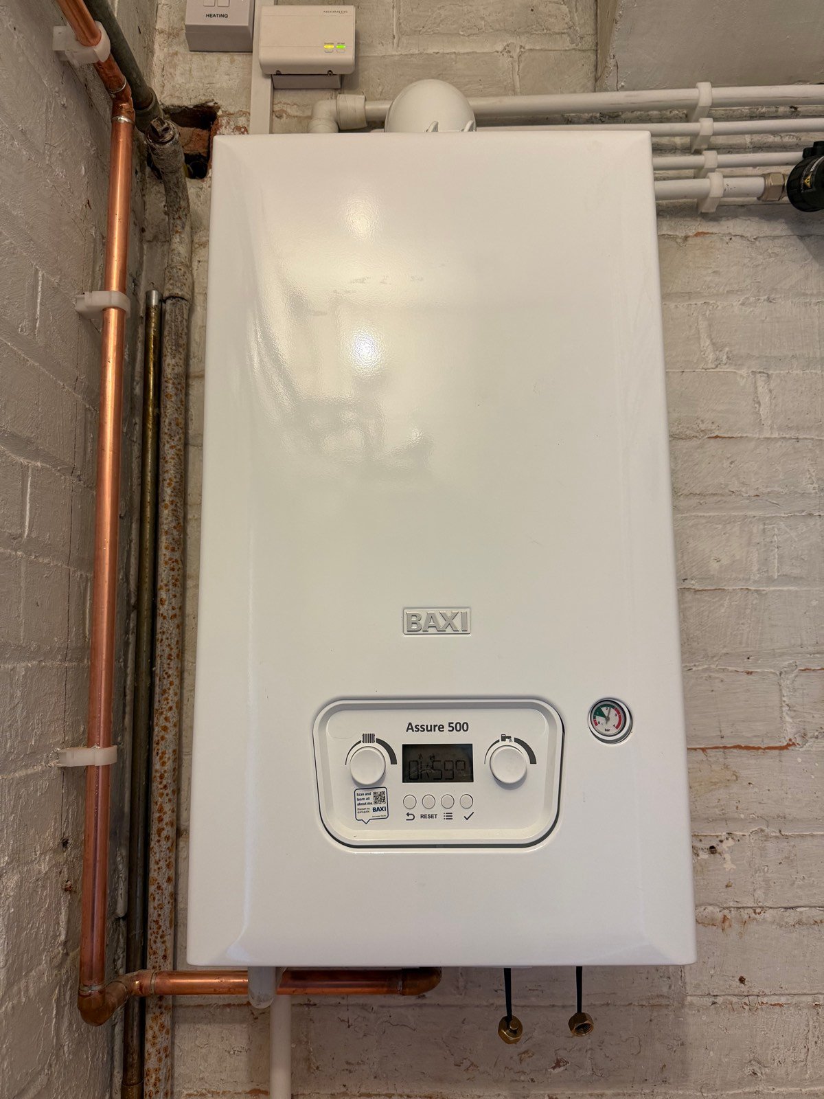 Combi boiler with copper pipework installed on a brick wall