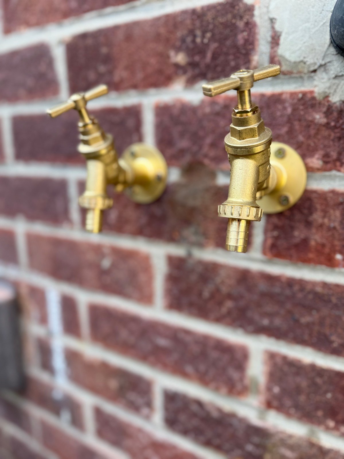 Outdoor brass tap installation on a brick wall